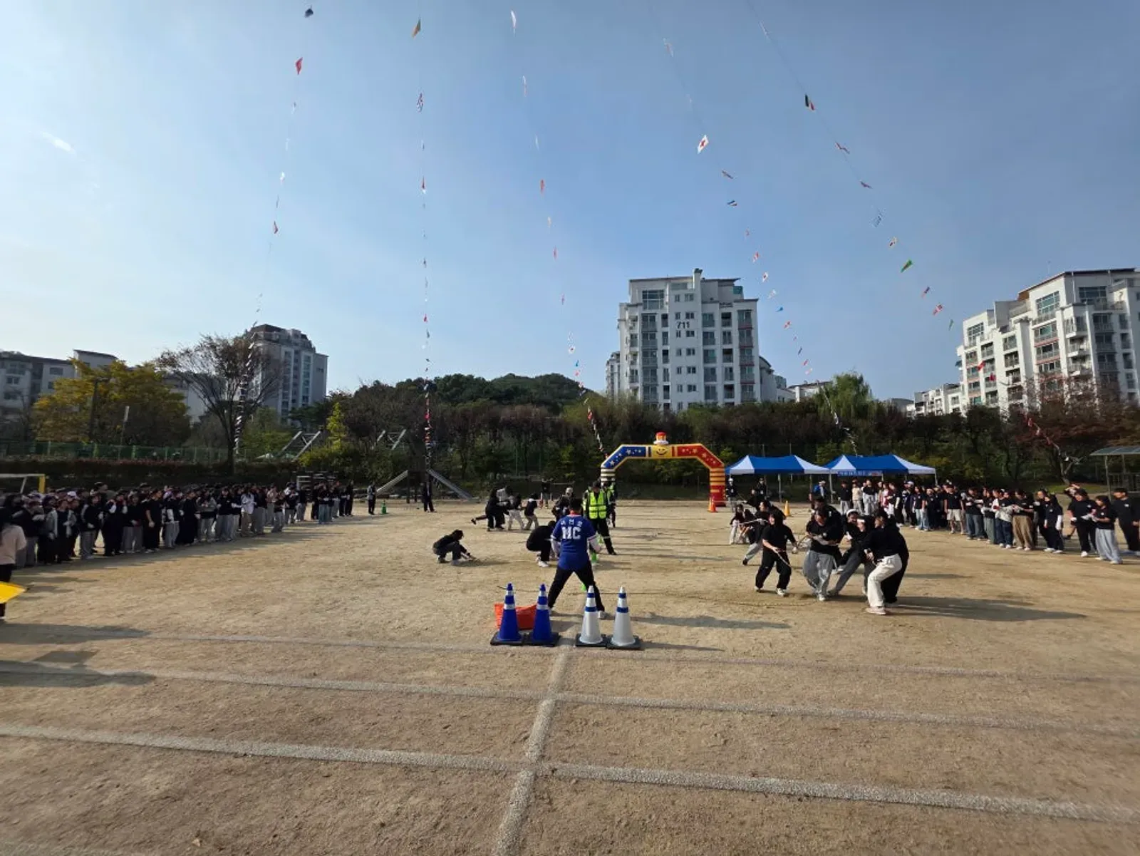 운동장 가운데 라바콘을 세우고 학생들이 달리며 응원하는 이어달리기 장면