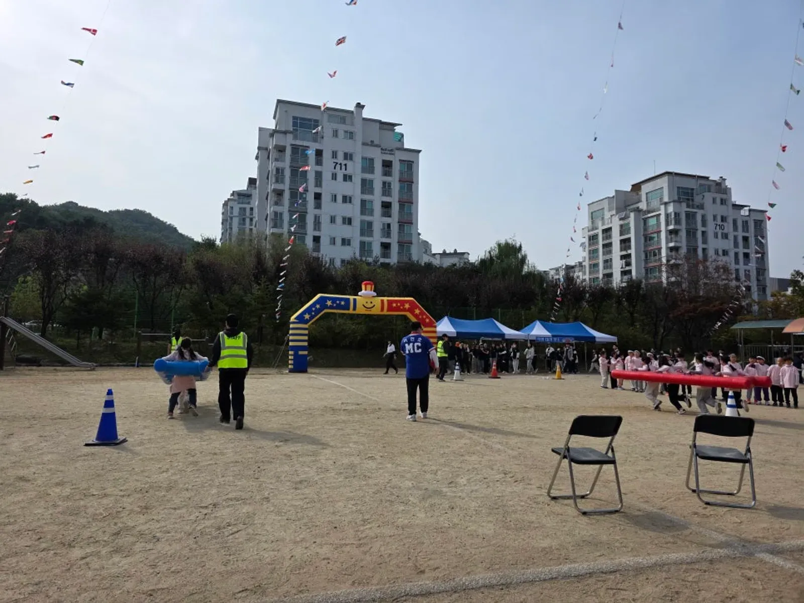 운동장 출발선에 접이식 의자 두 개와 라바콘을 두고 진행 요원이 경기를 준비하는 모습